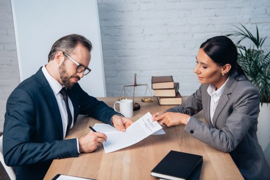 Business man signing a BOP insurance policy at a lawyers office in the Woodlands