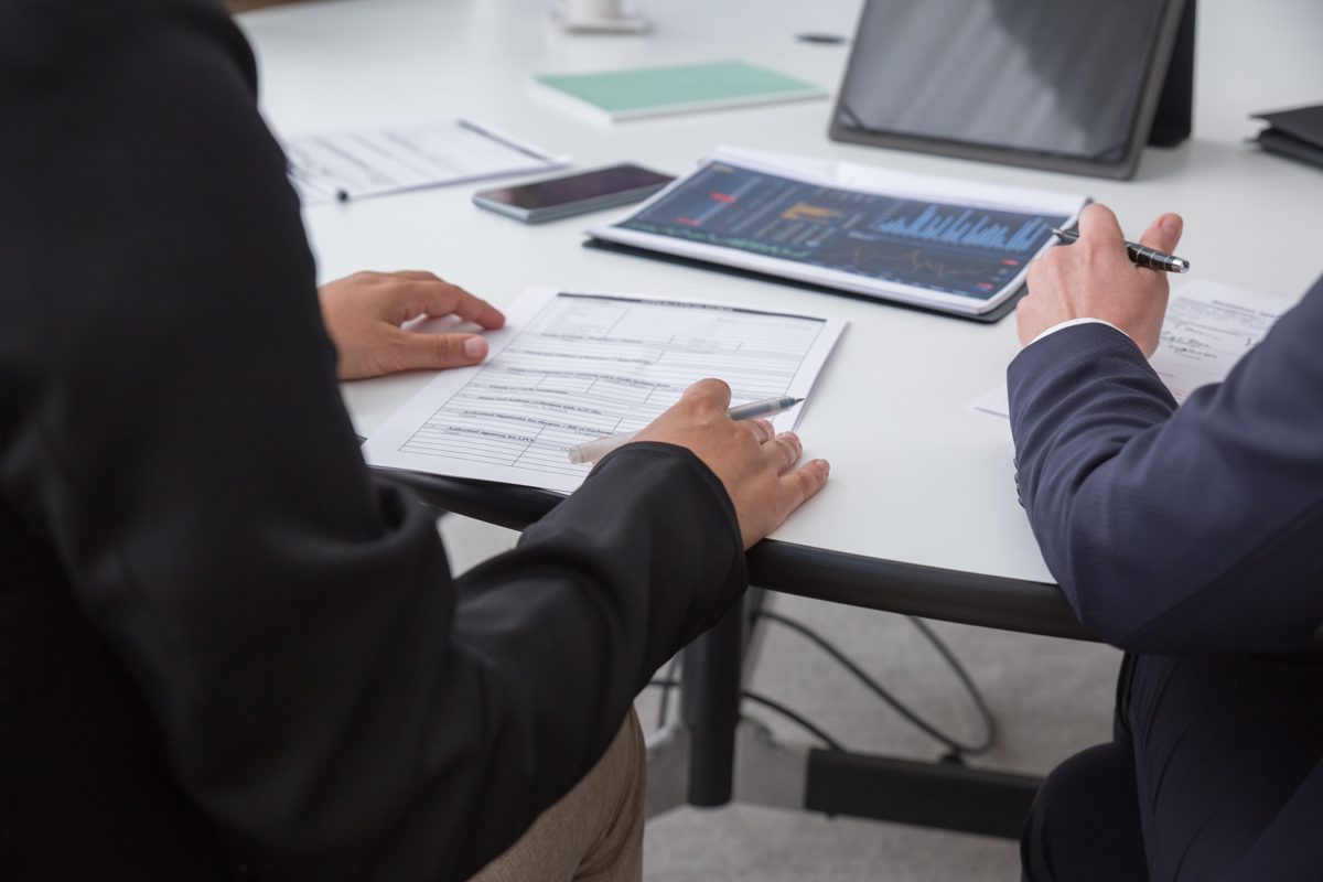Employer and insurance agent reviewing group health insurance premiums and renewal paperwork