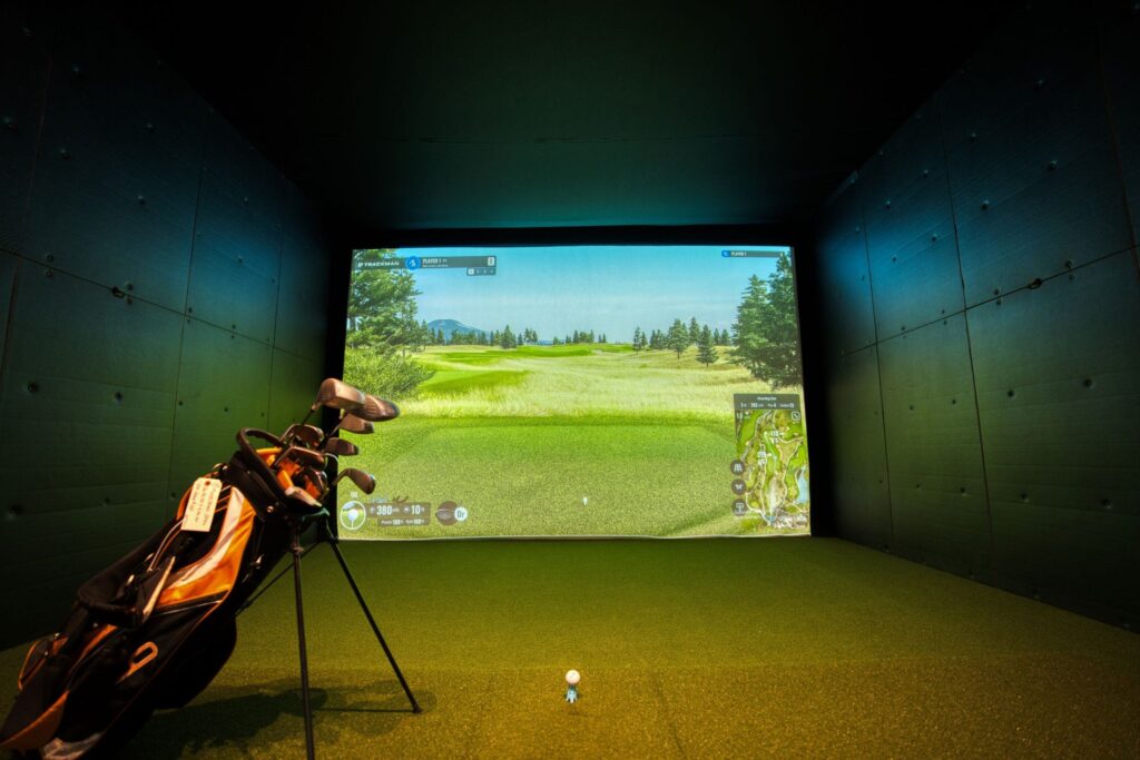 Golfer swinging at an indoor golf simulator screen, golf simulator insurance