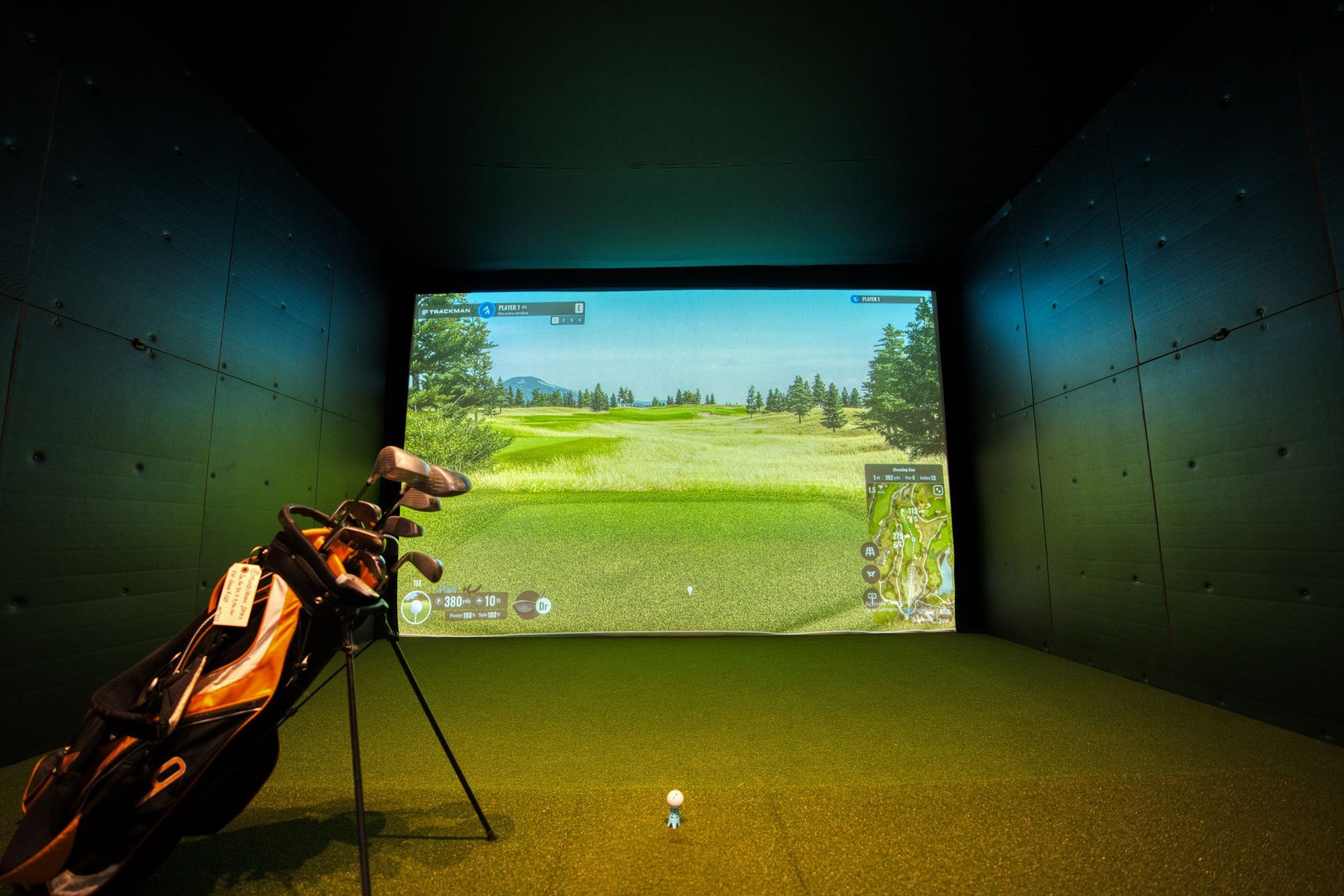 Golfer swinging at an indoor golf simulator screen, golf simulator insurance