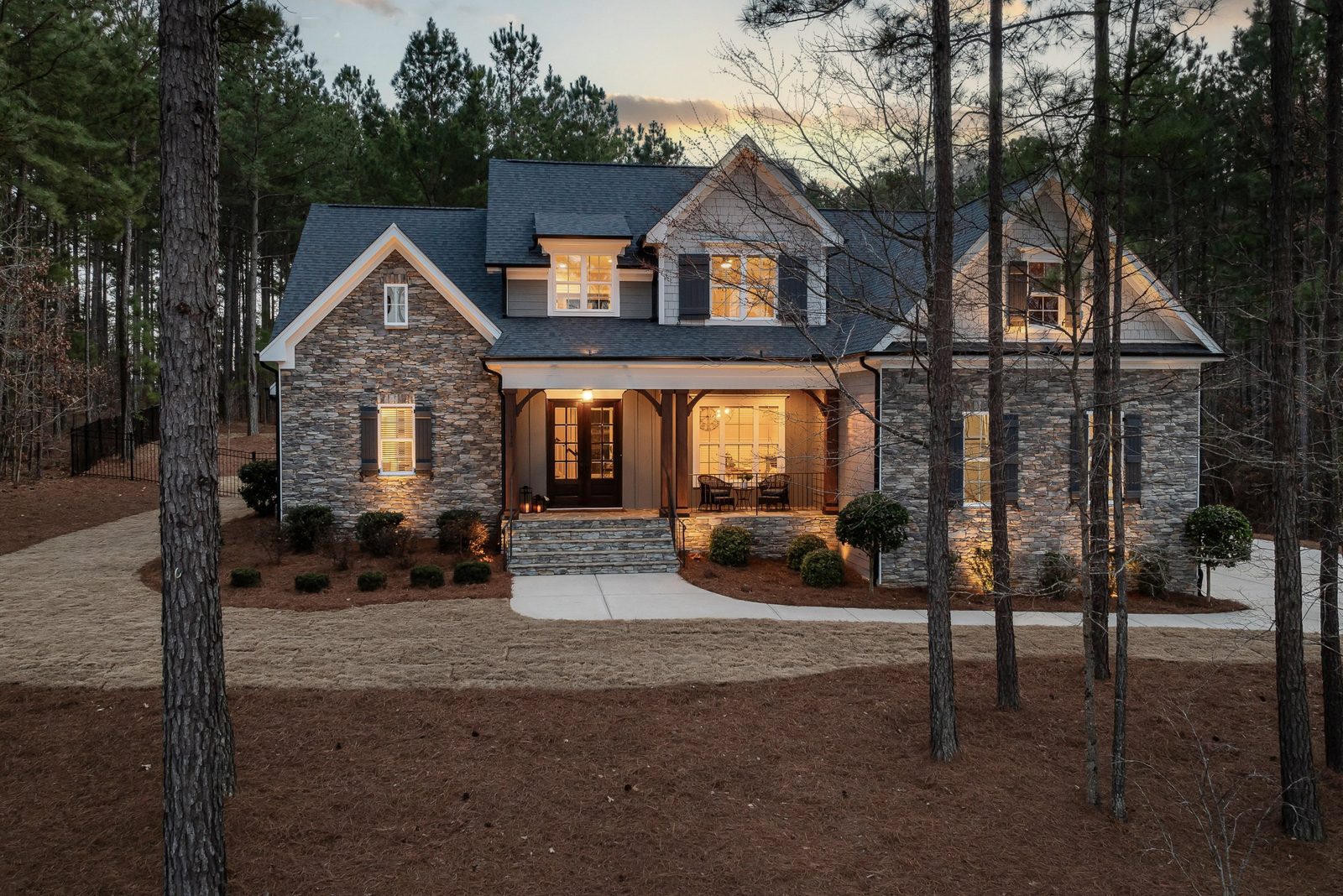 Stone house in a pine forest at dusk with warm lights on, showing what is insurance for: peace of mind at home